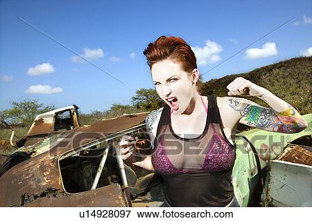 Angry tattooed Caucasian woman yelling with fists clenched in junkyard. View Large Photo Image Stock Photo - Angry tattooed Caucasian woman yelling with fists clenched in junkyard.. Fotosearch