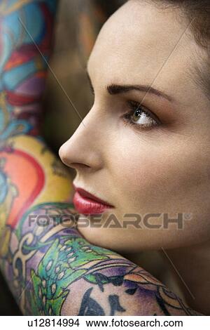 Close-up of attractive Caucasian woman's face and tattooed arm. View Large Photo Image Picture - Close-up of attractive Caucasian woman's face and tattooed arm.. Fotosearch