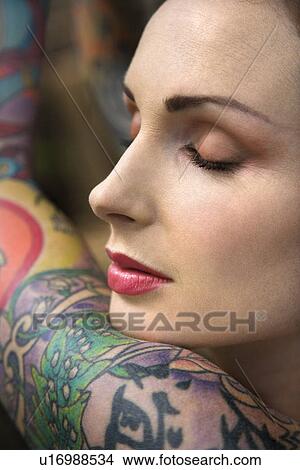 Close-up portrait of attractive woman's face and tattooed arm. View Large Photo Image Picture - Close-up portrait of attractive woman's face and tattooed arm.. Fotosearch