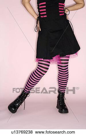 Stock Photo - Lower body portrait of Hispanic woman wearing striped leggings against pink background.. Fotosearch