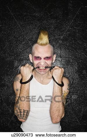 Mid-adult Caucasian male punk biting handcuffs. View Large Photo Image Stock Image - Mid-adult Caucasian male punk biting handcuffs.. Fotosearch
