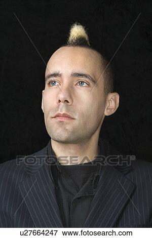 Stock Photo - Portrait of Caucasian man in suit with mohawk against black background.. Fotosearch