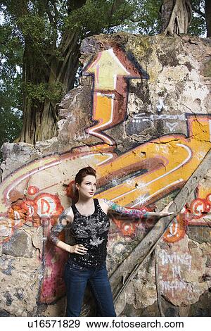 Sexy tattooed Caucasian woman standing next to wall covered in graffiti and a tree branch. View Large Photo Image Stock Photo - Sexy tattooed Caucasian woman standing next to wall covered in graffiti and a tree branch.. Fotosearch