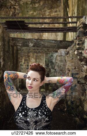 Stock Photograph - Sexy tattooed Caucasian woman standing next to concrete wall.. Fotosearch