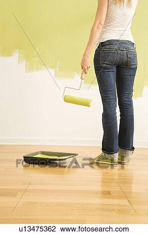 Back view of woman holding paint roller with half painted wall View Large Photo Image Stock Image - Back view of woman holding paint roller with half painted wall . Fotosearch