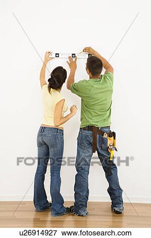 Stock Photo - Couple holding level to wall . Fotosearch
