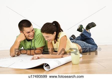 Couple lying on floor with coffee and looking at blueprints View Large Photo Image Stock Photo - Couple lying on floor with coffee and looking at blueprints. Fotosearch