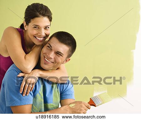 Stock Photography - Happy smiling couple painting interior wall of home. Fotosearch