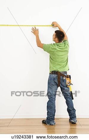 Man wearing tool belt measuring interior wall View Large Photo Image Stock Image - Man wearing tool belt measuring interior wall. Fotosearch