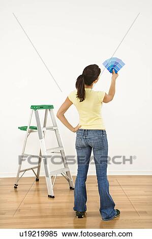 Woman standing in front of white interior wall with paint sample cards trying to choose color. View Large Photo Image Stock Photography - Woman standing in front of white interior wall with paint sample cards trying to choose color.. Fotosearch