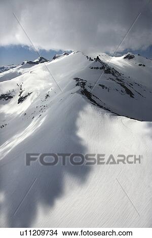 Aerial of snow covered mountain with clouds View Large Photo Image Picture - Aerial of snow covered mountain with clouds. Fotosearch