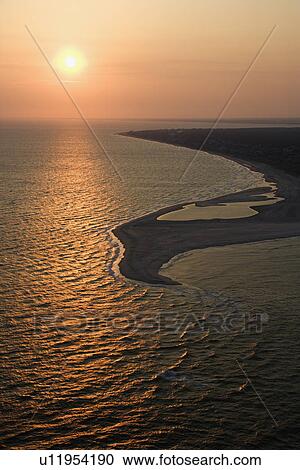 Stock Image - Aerial view of sun over Atlantic ocean and shoreline of Bald Head Island, North Carolina. Fotosearch