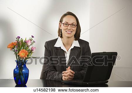 Stock Photo - Businesswoman sitting at desk with a laptop. Fotosearch