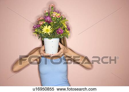 Stock Photography - Female holding pot of flowers in front of her face. Fotosearch