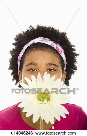Stock Photograph - Girl holding large Gerbera Daisy over face and looking at camera. Fotosearch
