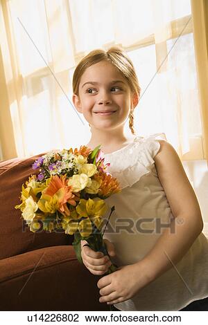 Stock Image - Girl smiling holding bouquet of flowers. Fotosearch