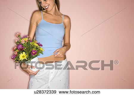 Stock Photo - Holding pot of flowers at hip. Fotosearch