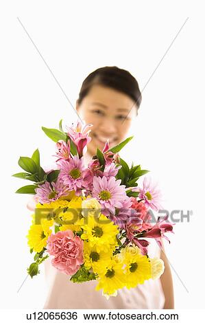 Stock Photograph - Mid adult woman holding out bouquet of flowers.. Fotosearch