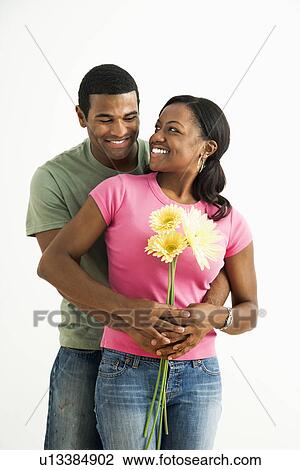 Stock Image - Portrait of smiling couple standing looking at each other.. Fotosearch