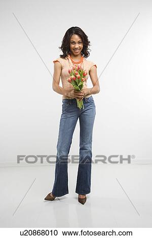 Stock Image - Woman holding bouquet of tulips smiling. Fotosearch