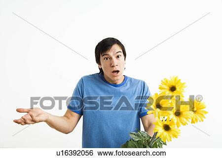 Young man holding bouquet of yellow gerbera daisies shrugging. View Large Photo Image Stock Photograph - Young man holding bouquet of yellow gerbera daisies shrugging.. Fotosearch