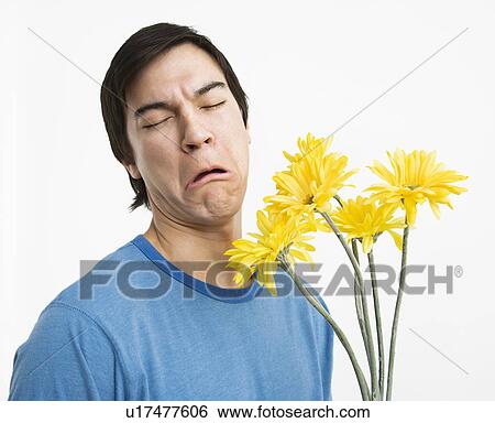 Stock Photograph - Young man holding bouquet of yellow gerbera daisies with bad look on his face.. Fotosearch