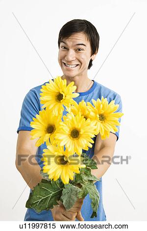 Young man holding bouquet of yellow gerbera daisies smiling. View Large Photo Image Stock Photography - Young man holding bouquet of yellow gerbera daisies smiling.. Fotosearch
