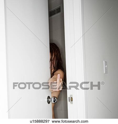Stock Photo - Caucasian woman in partially opened door making vulgar gesture at viewer.. Fotosearch
