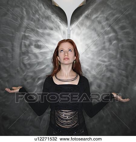 Stock Image - Woman in meditation pose looking up at parted metal background. Fotosearch