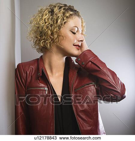 Stock Image - Woman in red jacket with hand touching face. Fotosearch