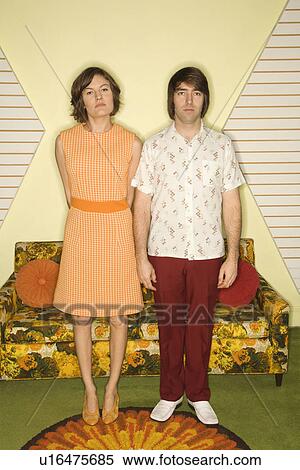 Caucasian mid-adult couple wearing retro clothes standing stiffly in room decorated with vintage furniture. View Large Photo Image Stock Photography - Caucasian mid-adult couple wearing retro clothes standing stiffly in room decorated with vintage furniture.. Fotosearch