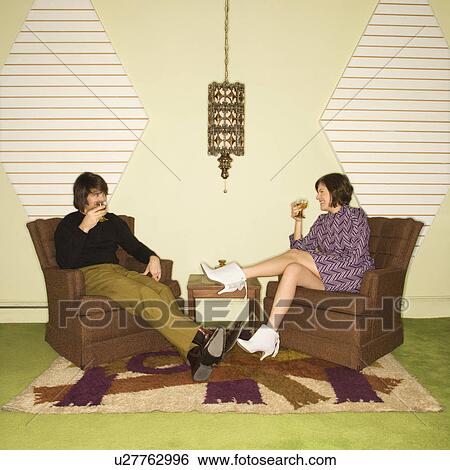 Caucasian mid-adult man and woman wearing vintage clothing seated in brown retro chairs smiling and drinking. View Large Photo Image Stock Photograph - Caucasian mid-adult man and woman wearing vintage clothing seated in brown retro chairs smiling and drinking.. Fotosearch
