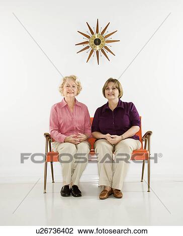 Stock Image - Caucasian middle aged woman and senior woman sitting together.. Fotosearch