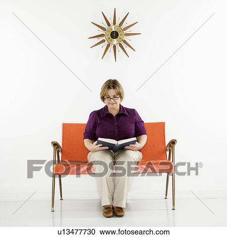 Stock Image - Caucasian middle aged woman sitting reading book.. Fotosearch