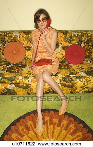 Pretty Caucasian mid-adult woman wearing sunglasses sitting on colorful retro sofa talking on red telephone. View Large Photo Image Stock Image - Pretty Caucasian mid-adult woman wearing sunglasses sitting on colorful retro sofa talking on red telephone.. Fotosearch