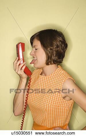 Pretty Caucasian mid-adult woman wearing orange dress sticking out tongue at red telephone receiver. View Large Photo Image Stock Image - Pretty Caucasian mid-adult woman wearing orange dress sticking out tongue at red telephone receiver.. Fotosearch