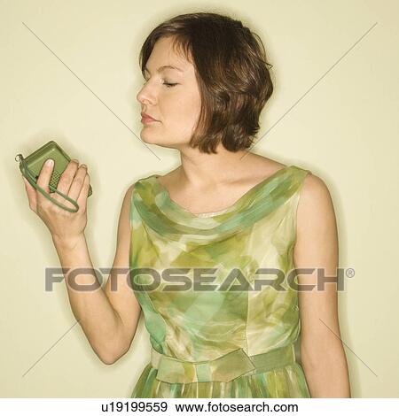 Pretty Caucasian mid-adult woman wearing green vintage dress looking at handheld radio. View Large Photo Image Stock Photo - Pretty Caucasian mid-adult woman wearing green vintage dress looking at handheld radio.. Fotosearch
