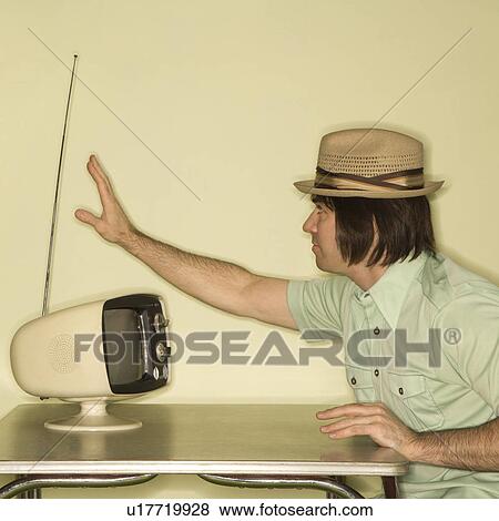 Side view of Caucasian mid-adult man wearing hat sitting at 50's retro dinette set adjusting old television antenna. View Large Photo Image Stock Photo - Side view of Caucasian mid-adult man wearing hat sitting at 50's retro dinette set adjusting old television antenna.. Fotosearch