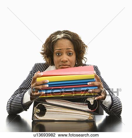 Stock Image - Businesswoman resting head on large stack of books and files looking overwhelmed. Fotosearch