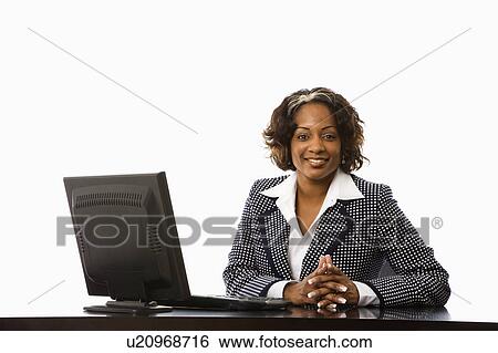Stock Photograph - Businesswoman sitting at desk with computer smiling. Fotosearch