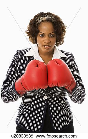 Businesswoman wearing boxing gloves looking serious View Large Photo Image Stock Photography - Businesswoman wearing boxing gloves looking serious. Fotosearch
