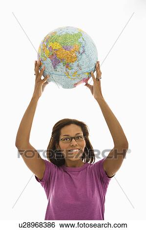 Stock Photograph - Woman holding globe over head and smiling at viewer. Fotosearch