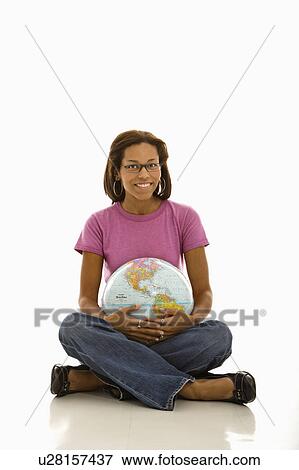 Stock Photo - Woman sitting on floor holding globe and smiling at viewer. Fotosearch