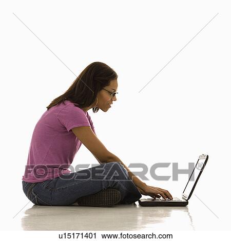 Stock Image - Woman sitting on floor using laptop. Fotosearch