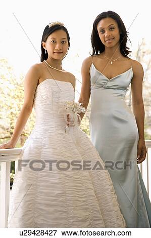 A portrait of a African-American maid of honor and Asian bride leaning against railing. View Large Photo Image Stock Photo - A portrait of a African-American maid of honor and Asian bride leaning against railing.. Fotosearch