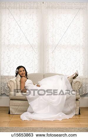 Stock Image - African-American bride lying on love seat.. Fotosearch