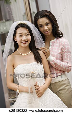 Asian bride and African-American friend admiring dress in mirror. View Large Photo Image Stock Image - Asian bride and African-American friend admiring dress in mirror.. Fotosearch
