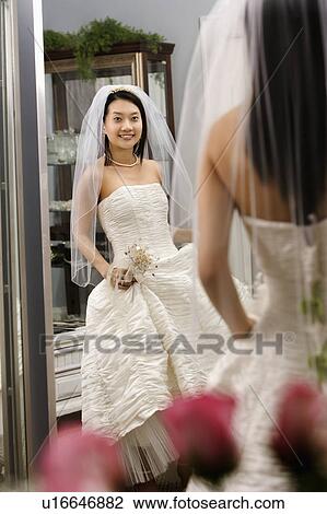 Stock Image - Bride admiring dress in mirror. Fotosearch