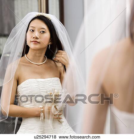 Bride looking at herself in a mirror View Large Photo Image Stock Photo - Bride looking at herself in a mirror. Fotosearch