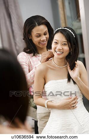 Friend helping place necklace on bride View Large Photo Image Picture - Friend helping place necklace on bride. Fotosearch